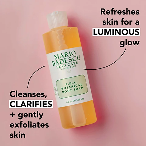 Image 1 - A bottle of Mario Badescu A.H.A. Botanical Body Soap is shown, with text highlighting its benefits: Refreshes skin for a LUMINOUS glow and Cleanses, CLARIFIES + gently exfoliates skin.
Image 2 - An arrangement of grapefruit halves, dried ginseng slices, and small droplets of oil, with the text rejuvenating grapefruit extract, invigorating + antioxidant-rich ginseng extract, and exfoliating glycolic acid.